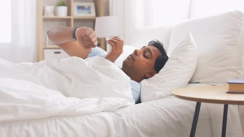 Man Waking Up and Stretching in Bed