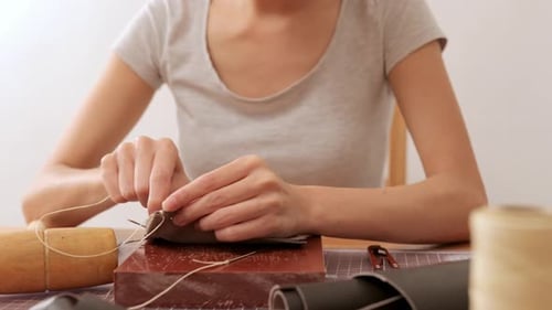 Woman Sewing Leather Together at a Table