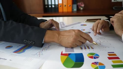 Geschäftsmann untersucht Grafiken mit anderen Arbeitern.
