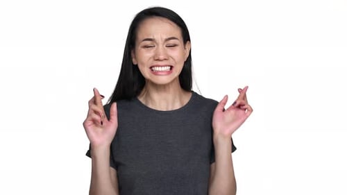 Woman Crossing Fingers and Smiling on White Background