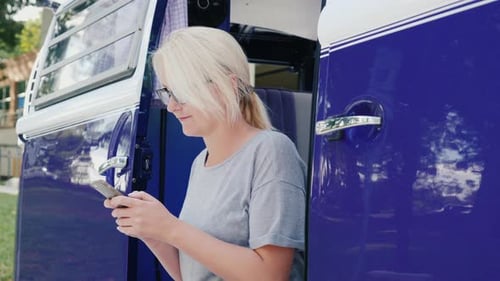 Woman Using Mobile Phone in Blue and White Van