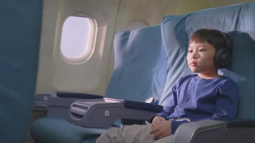 Boy on Plane Wearing Headphones Looking Out Window