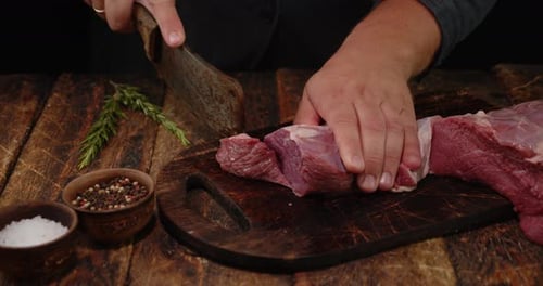 Butcher Cuts Raw Meat on Wooden Cutting Board