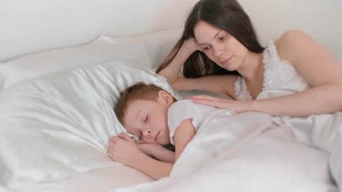 Mother Comforts Sleeping Child in Bed
