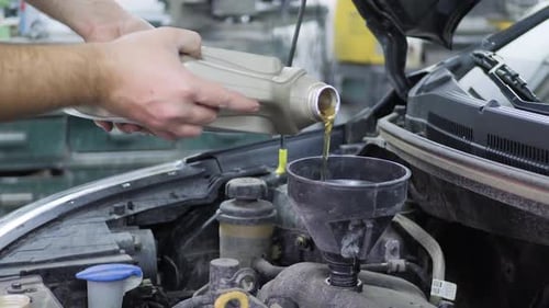 Mechanic Pours Oil Into a Car Engine