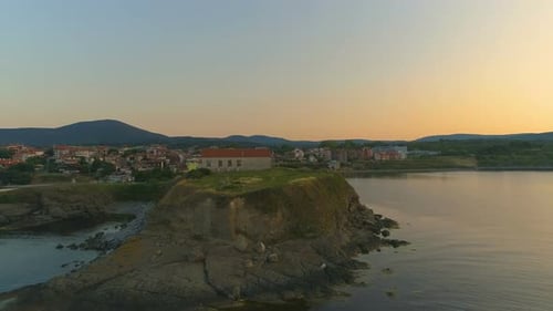 Felsige Küste und Berge im Hintergrund bei Sonnenuntergang