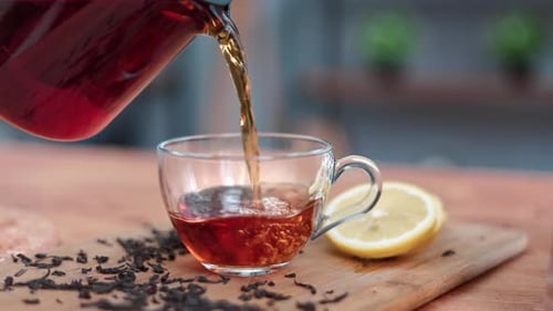 Teapot Pouring Tea into Clear Glass Mug