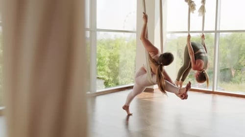 Women Doing Aerial Yoga in Bright Studio