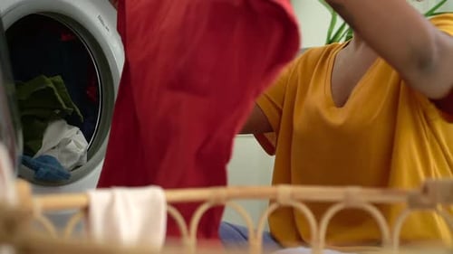 Closeup View of Young Housewife Putting Dirty Clothes in Washing Machine in Laundry at Home Spbd