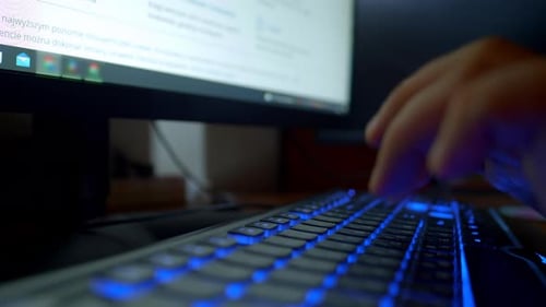 Primer plano de las manos masculinas escribiendo en el teclado de una computadora