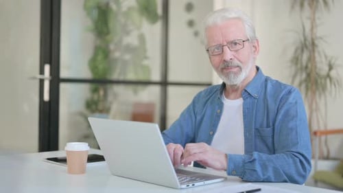 Senior Man Smiling While Using Laptop Computer