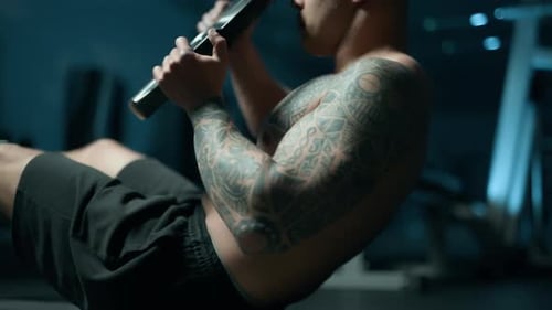 A Handsome Young Muscular Sportsman is Doing Exercise on a Fitness Machine in the Gym