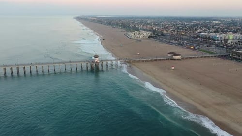 4k ariel drone shot heading straight down the pier in California, Surf City USA as a military troop