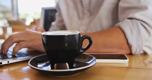 Mann benutzt Laptop bei einer Tasse Kaffee