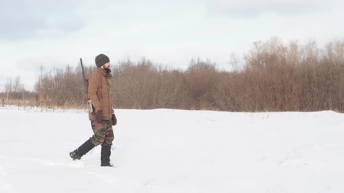 Male Warm Clothes Walking on the Field with Hunting Rifle.