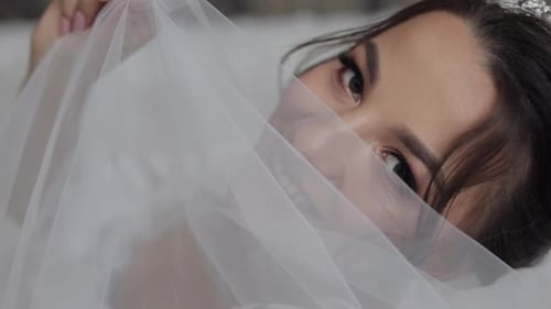 Smiling Bride Peeks Through Veil During Wedding Preparation