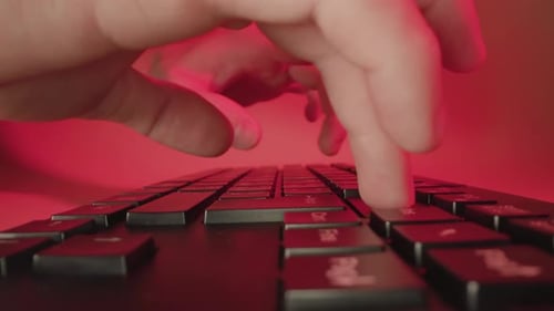 Fingers Typing on Keyboard in Red Lit Room