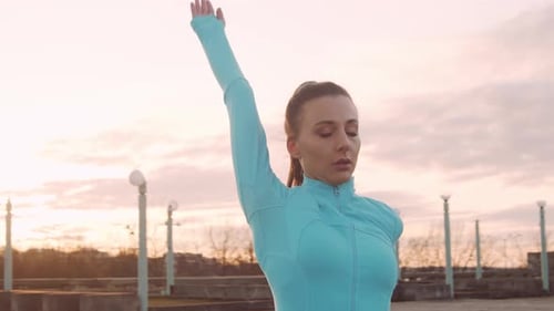 Woman Stretching Arms Outdoors at Sunrise or Sunset