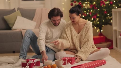 Couple Wrapping Christmas Presents in Cozy Living Room