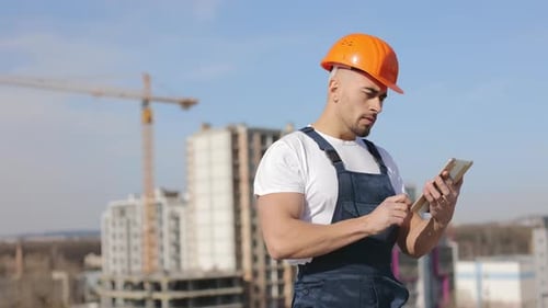 Portrait of a Young Engineer Who is Working on the Tablet