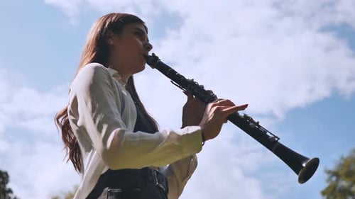 Girl Plays Clarinet Against Sky