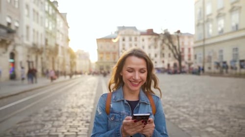 Woman Walking Down an Old Street Using Smartphone and Is Very Happy That She Sees There. Win or Big