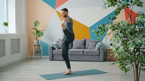 Man Does Yoga Pose on Mat Indoors