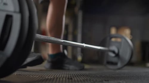 Un atlético anónimo realiza un peso muerto con una barra, levanta una barra y hace entrenamiento con pesas en