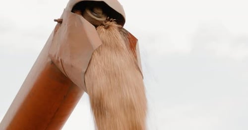 Harvester Unloading Grains Against Sky