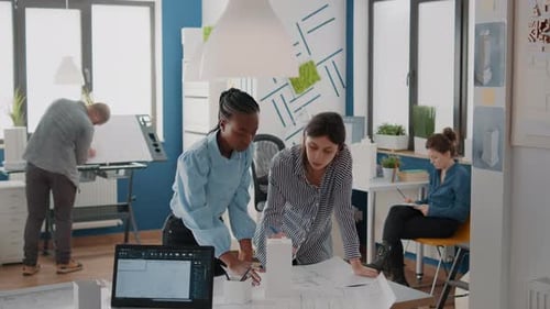 Team of Workmates Looking at Building Model and Blueprints Plans on Table