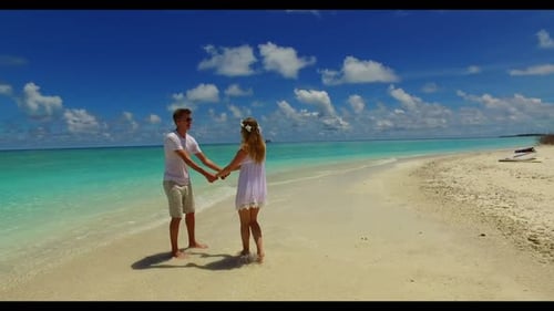 Young couple in love on exotic tourist beach holiday by turquoise water with white sandy background