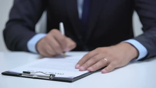 Man Signing Divorce Decree, Angrily Taking Off Wedding Ring, Property Division