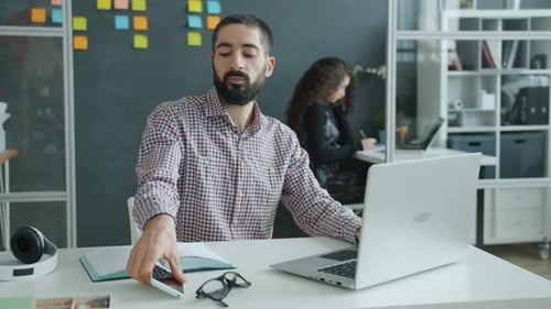 Slow Motion of Young Mixed Race Man Using Laptop Then Talking on Mobile Phone in Shared Office