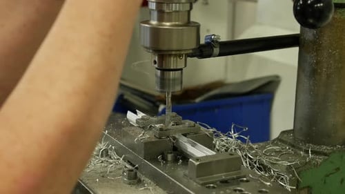 Arbeiter bohrt mit einer Stanzbohrmaschine Löcher in Metallplatten