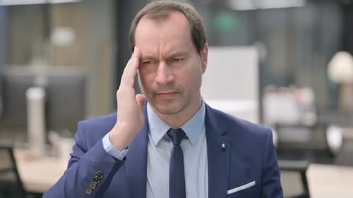 Businessman Experiencing Headache in Modern Office