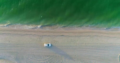 Car drives along the sandy seashore. Aerial view