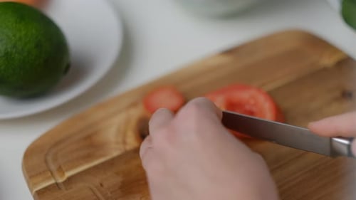 Close-up of Female hands cut a tomato Cooking Salad.
