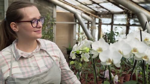 Woman Smiles Among the Flowers in Greenhouse