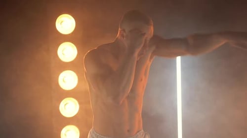 Muscular Man Shadow Boxing in Smoky Gym with Lights