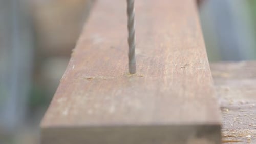Drill bit bores into wooden plank