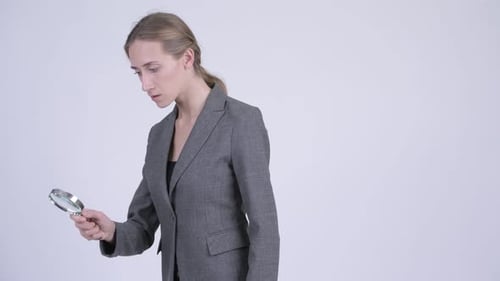 Junge blonde Geschäftsfrau mit Lupe