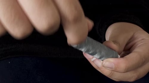 Close Up of Hands Unwinding Gray Thread