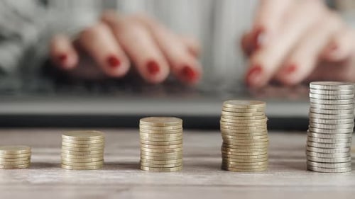 Stack of Coins With Laptop Typing