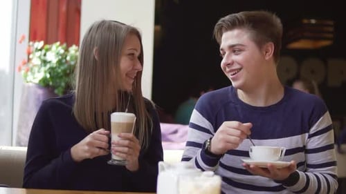Young Smiling Couple in Outdoor Coffee Shop Smiling and Drinking Coffee