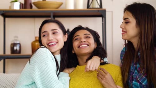 Three Friends Embracing and Laughing Indoors
