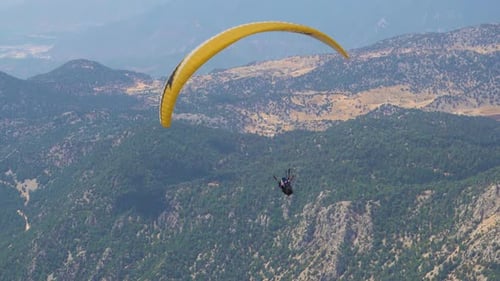 Paragliders fly over mountain top in epic scenery. Parachutes or paragliding experience. Adrenaline