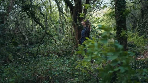Woman Exploring the Forest Path with Wild Grass and Old Trees in the Background