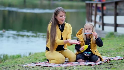 Mother and Child Making Bubbles by the Lake