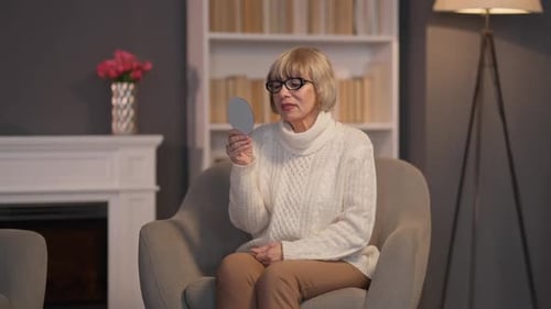 Senior Woman Examining Face in Mirror Indoors