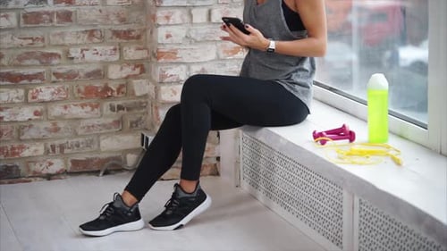 Woman Resting After Workout Using Smartphone Indoors